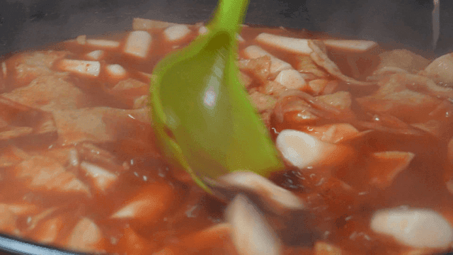 Ladle stirring spicy tteokbokki in pot