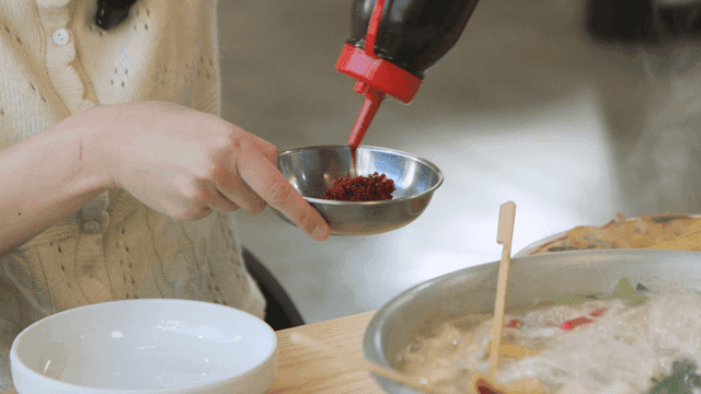 Woman adding soy sauce to small sauce bowl