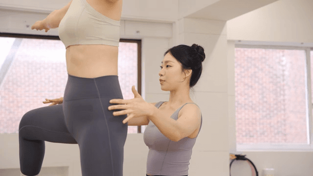Pilates instructor guiding a student indoors