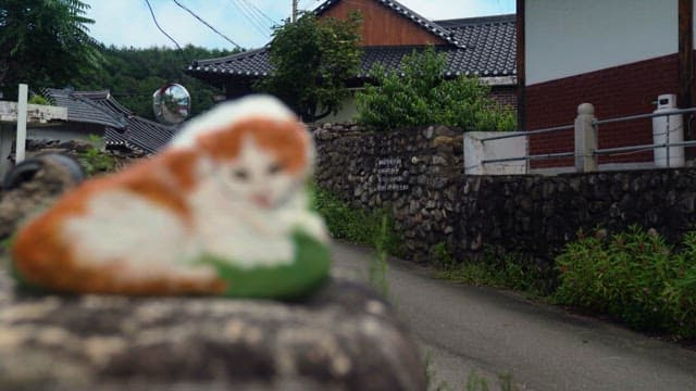 Painted cat on a stone wall in a quiet traditional house village alley