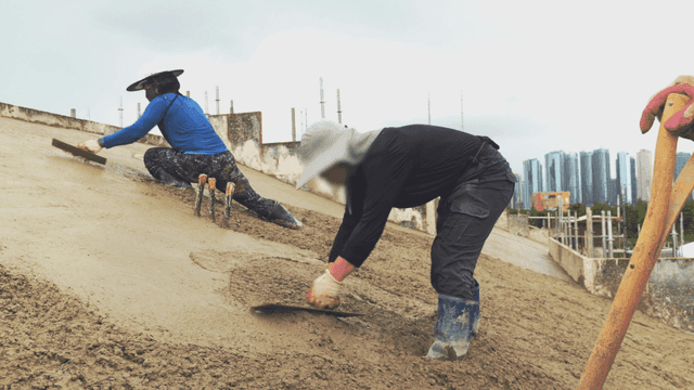 경사면에서 콘크리트를 다듬는 작업자들