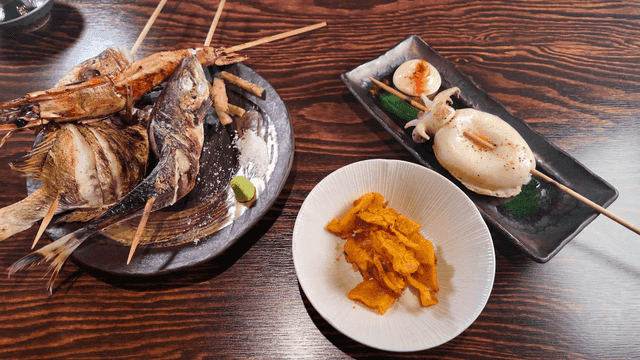Various grilled seafood skewers on wooden table