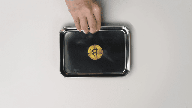 Hand offering a tray with a Bitcoin on it