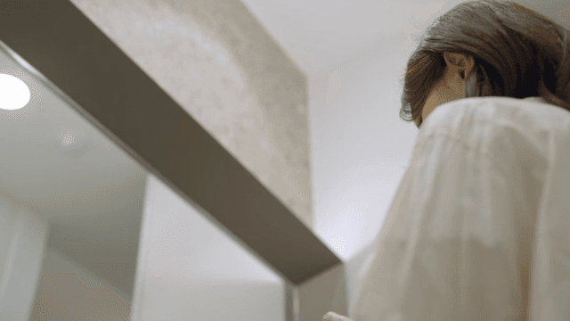 화장실에서 거울을 보며 머리를 정리하는 여성