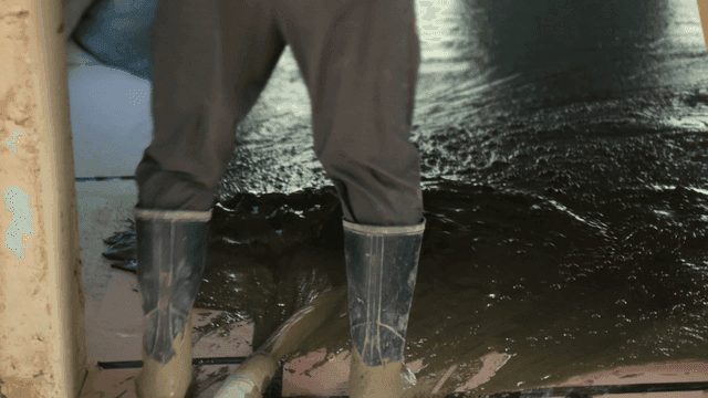 실내에서 젖은 콘크리트를 고르는 작업자