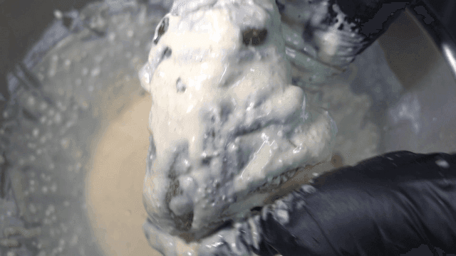 Glove-clad hands coating with batter