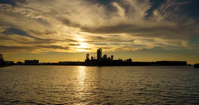 저녁부터 밤까지의 바다 근처에 위치한 산업단지 풍경