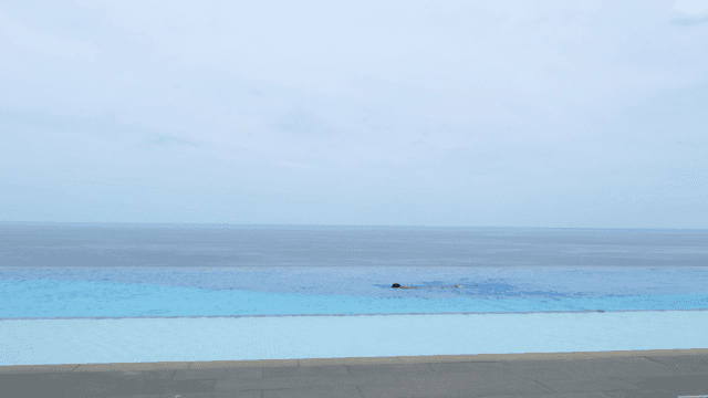 Person swimming in infinity pool overlooking ocean