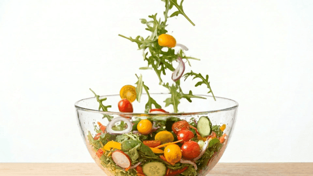 Fresh vegetables falling into a salad bowl