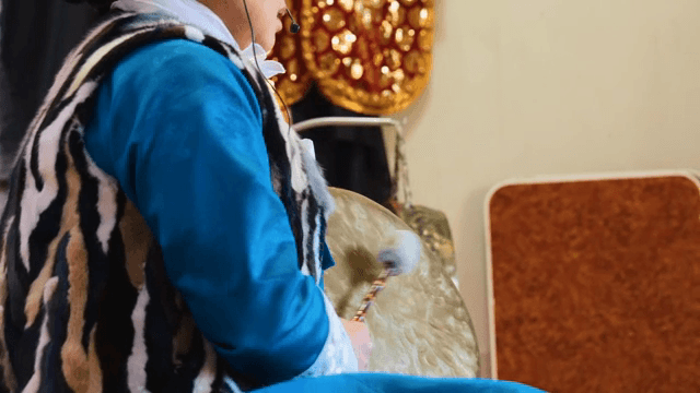 전통 의상을 입고 징을 치는 사람