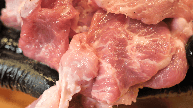 검은 장갑 위의 생 돼지고기 조각들