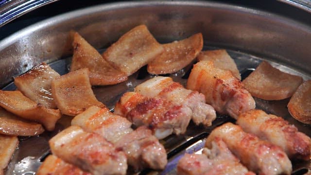 그릴에서 구워지는 삼겹살과 돼지껍데기