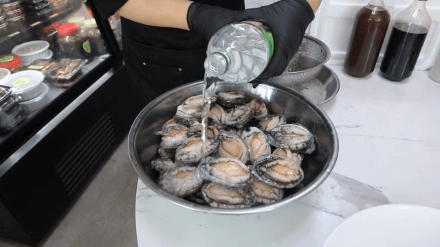 전복이 있는 그릇에 소주를 붓는 장면