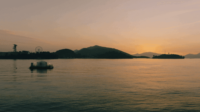 Sunset over a calm sea with distant hills