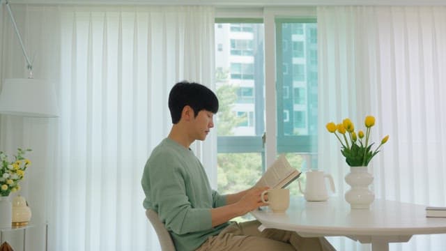 Man Reading a Book by the Window in Bright Living Room