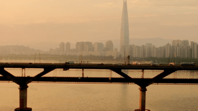 Bridge over a river with a city skyline at sunset