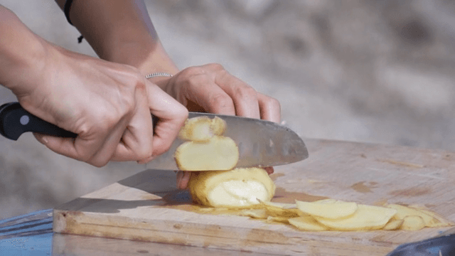 Slicing potatoes on a wooden cutting board