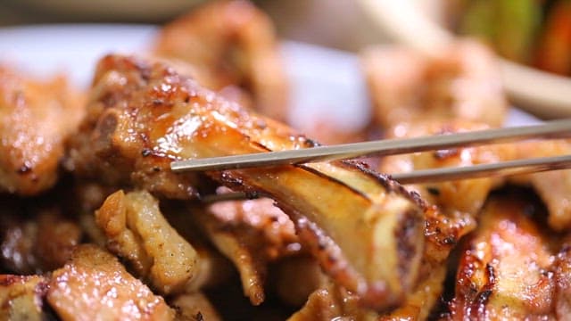 Grilled marinated pork ribs held with chopsticks