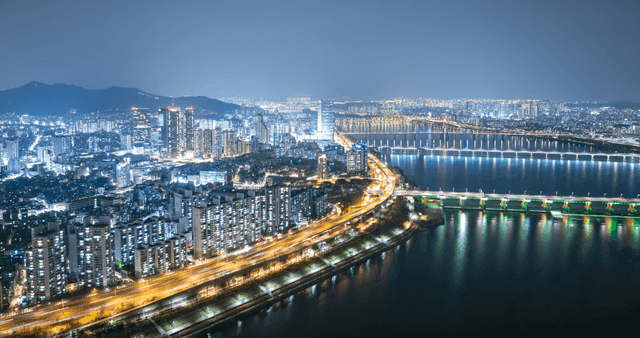 A vibrant cityscape with illuminated buildings and a river