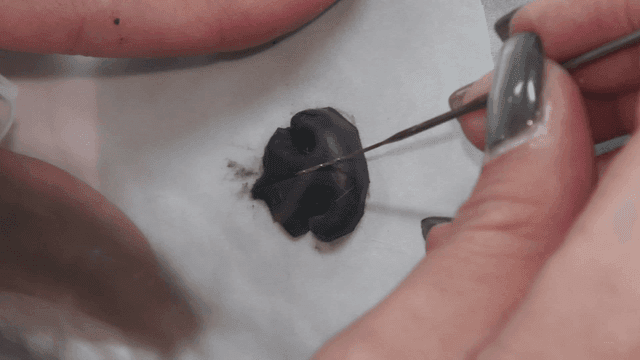 Hand shaping small puppy's nose with needle