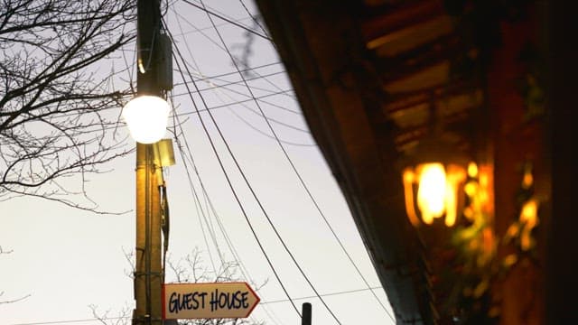 Evening street lamps lighting up near a guest house sign