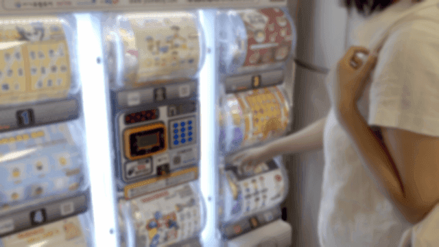 가챠샵 뽑기 기계들을 구경하는 사람