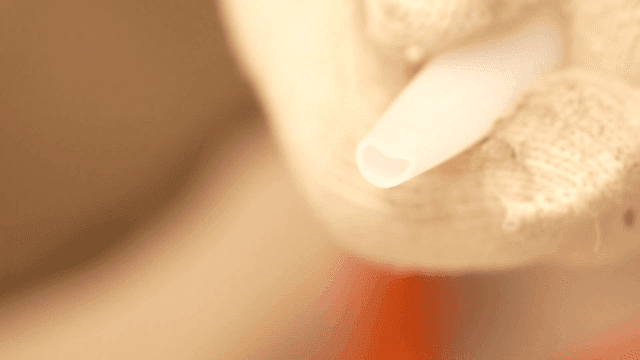 실리콘 건 노즐을 잡고 있는 장갑 낀 손의 클로즈업