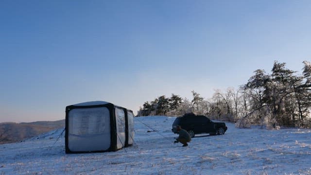 Man Setting Up a Tent in Snowy Landscape