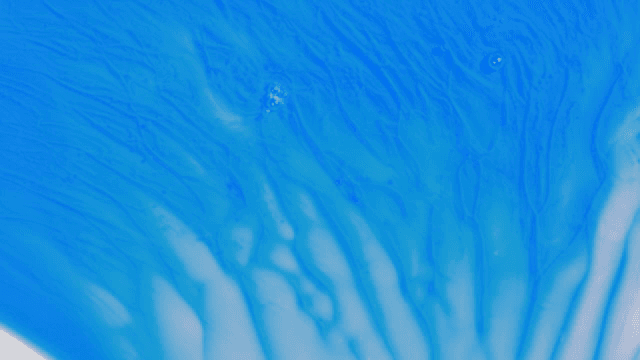 Abstract pattern of blue and white liquids mixing together