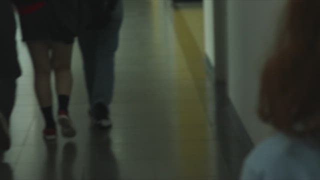 어두운 복도에서 흩어진 종이를 줍는 학생