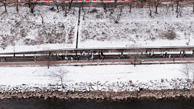 People jogging on a snowy riverside path