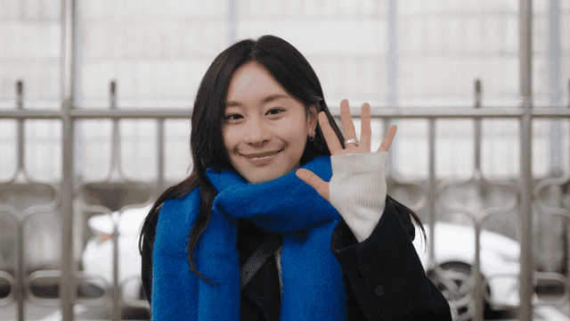 정면을 보고 미소 짓으며 손을 흔드는 여성