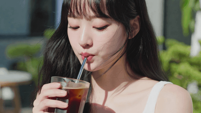 야외에서 차가운 아이스 아메리카노를 마시는 여성