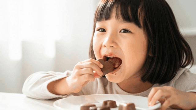 초콜릿을 먹고 행복해하는 여자 아이