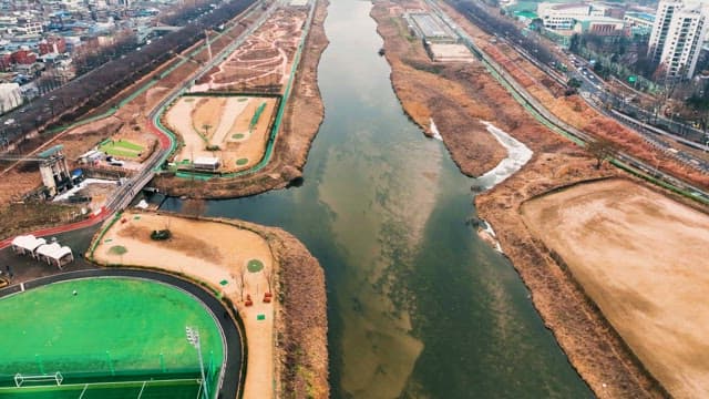 도로와 들판이 양옆으로 펼쳐진 도시 하천의 풍경