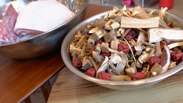 Various dried herbs and roots in a metal bowl