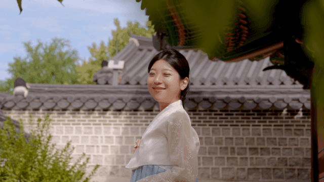 Woman in hanbok smiling in a traditional courtyard