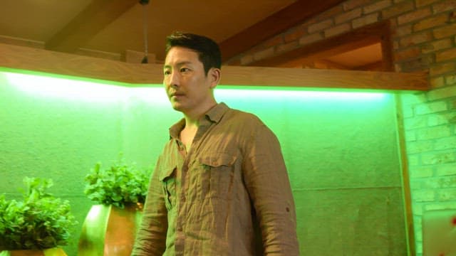 초록색 조명 실내에서 주변을 둘러보는 남자