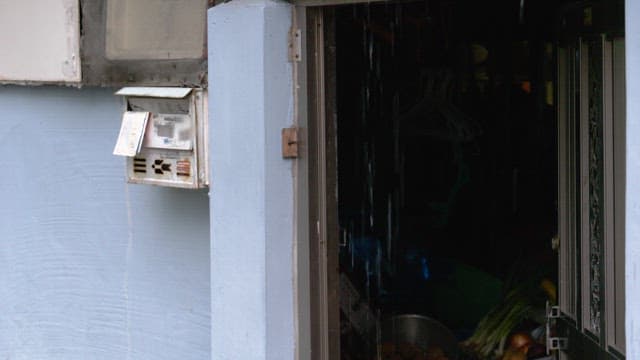 Rain falling on an old mailbox beside the door in narrow alley