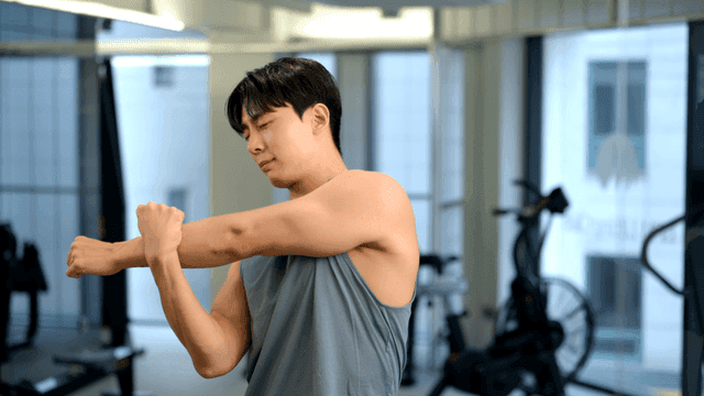 세련된 헬스장에서 팔 스트레칭하는 젊은 남성