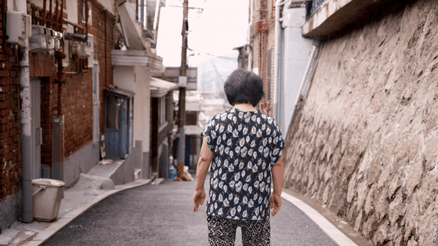 좁은 골목길을 걷는 노인 여성