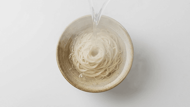 Bowl of noodles with hot broth poured over them