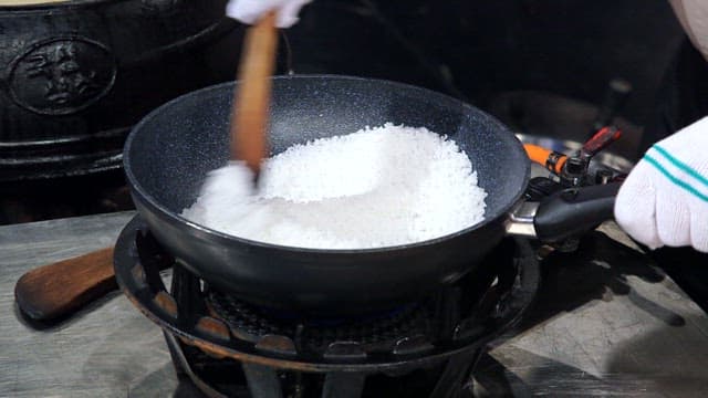 팬에서 소금을 저으며 요리하는 장면