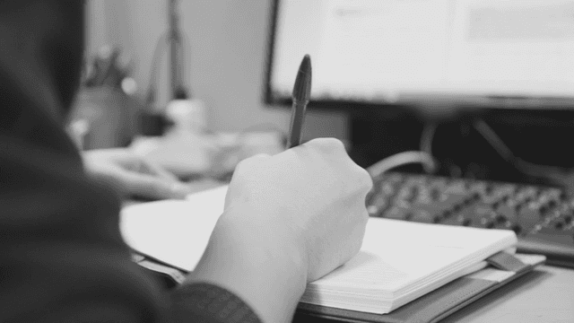 책상에서 메모를 하는 사람