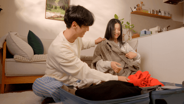 Couple organizing home with suitcase in cozy living room