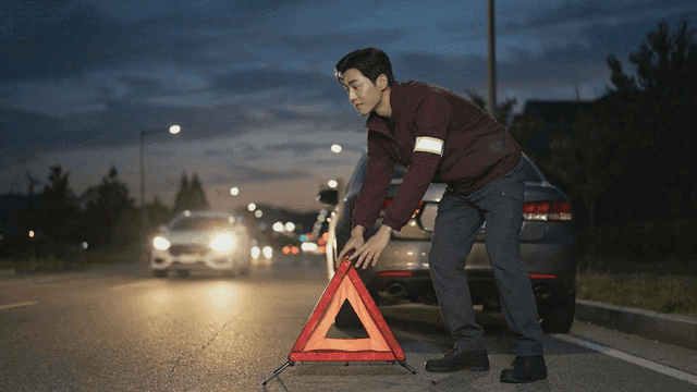 Man setting up a warning triangle by a car