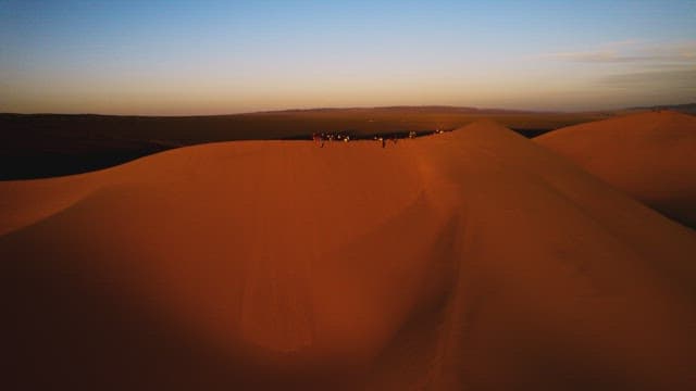 Sunset Over Desert Dunes with People