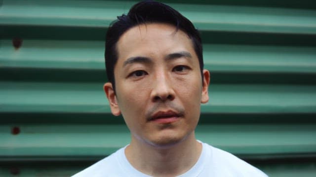 야외에서 녹색 벽 앞에 서있는 남자