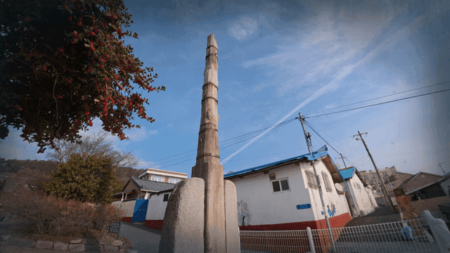 Tall stone monument under clear sky of quiet village
