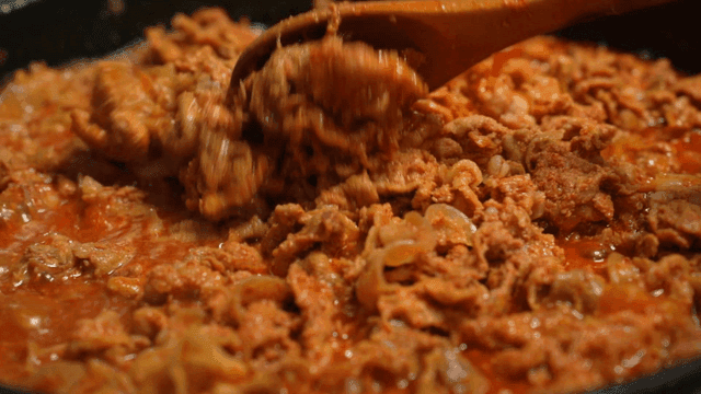 Spicy stir-fried pork cooking in pan